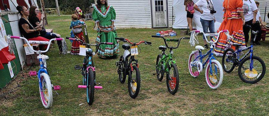 Bikes lined up for the Fiesta bike giveaway, with dancers in traditional dress nearby