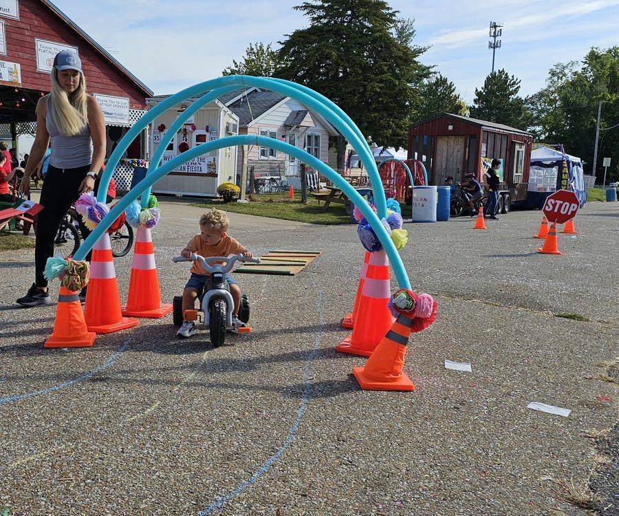 A child riding a scooter through the cone obstacle course