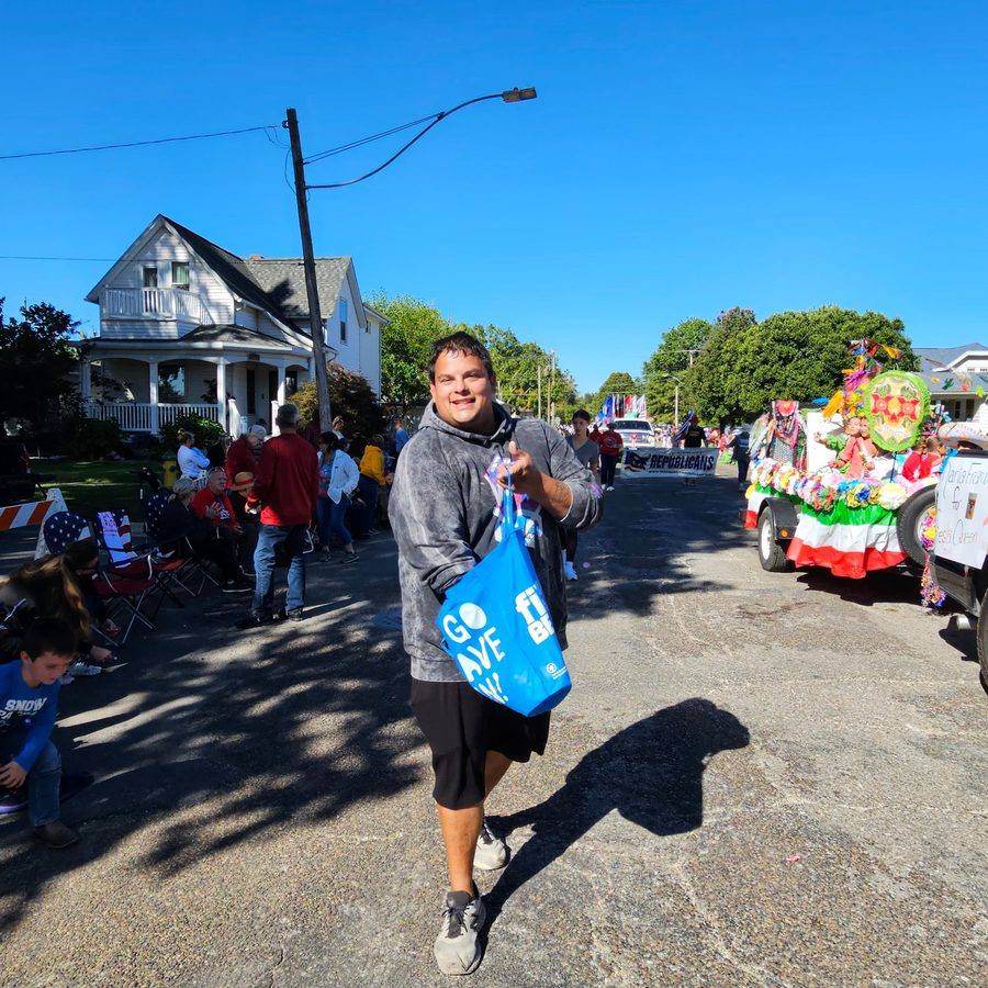 Parade-goers along the street with a Queen candidate float passing by
