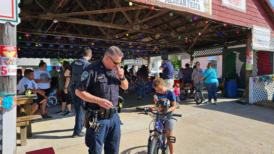 A Fort Madison police officer helping a child with a bike helmet
