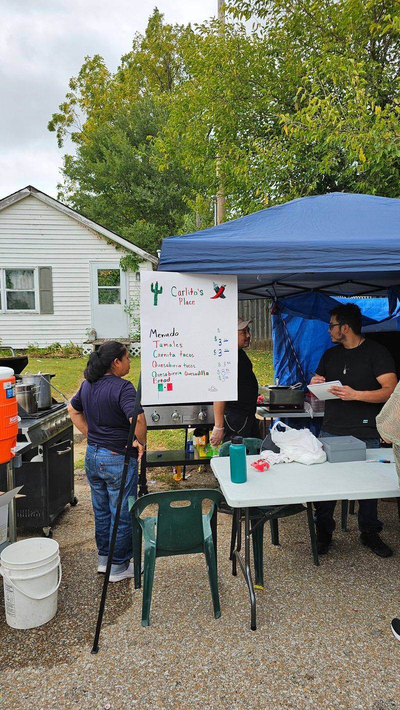 Carlito's Place food vendor menu board, offering menudo, tamales, and quesabirria tacos
