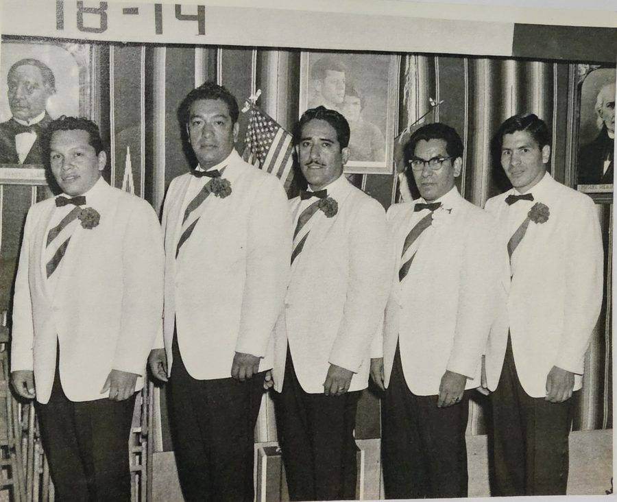 Archival black-and-white photo of five men in white formal jackets